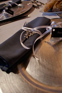 Décoration d'une table pour un mariage, gros plan sur une serviette noir avec un ruban et une fée en argent
